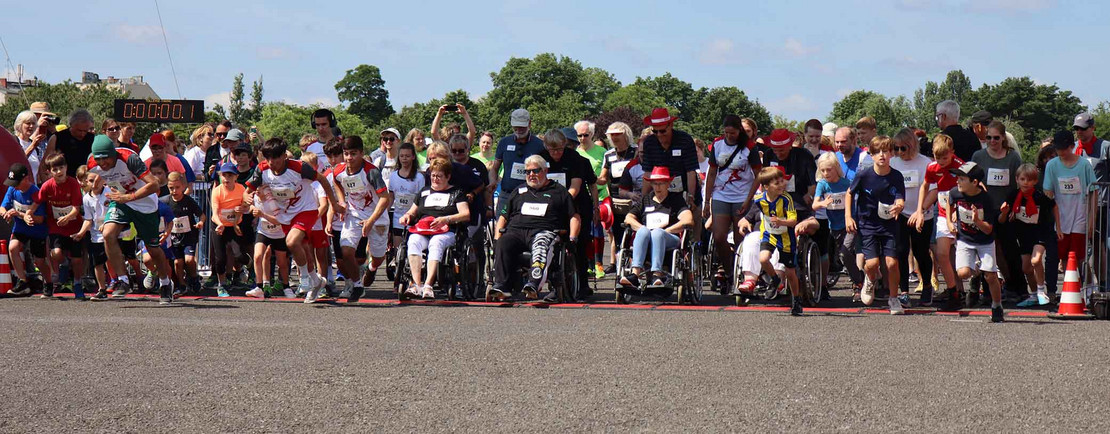 Viele Menschen, darunter Rollstuhlfahrer, an der Startlinie. 