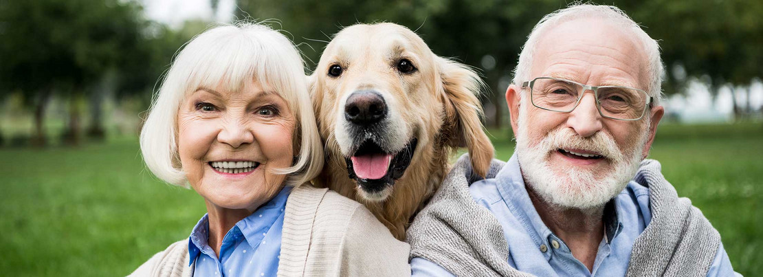 Älteres Ehepaar mit Hund lächelt in die Kamera 