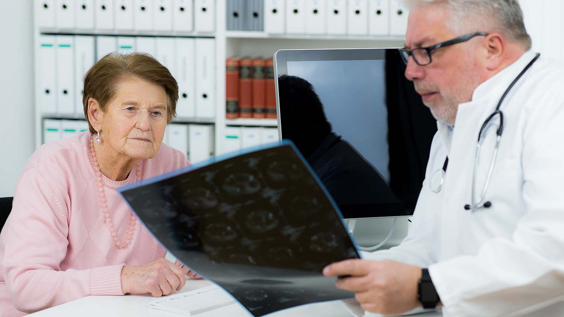 Arzt mit Röntgenaufnahmen im Gespräch mit einer älteren Patientin