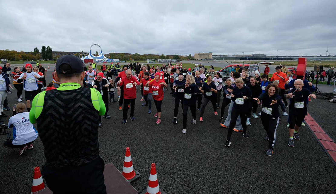 Mann steht auf einer Bühne und macht Übungen vor einer Gruppe. 