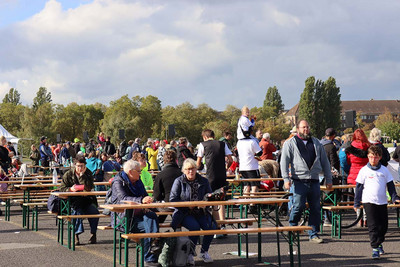 Personen sitzen an Bierzeltgarnituren. 