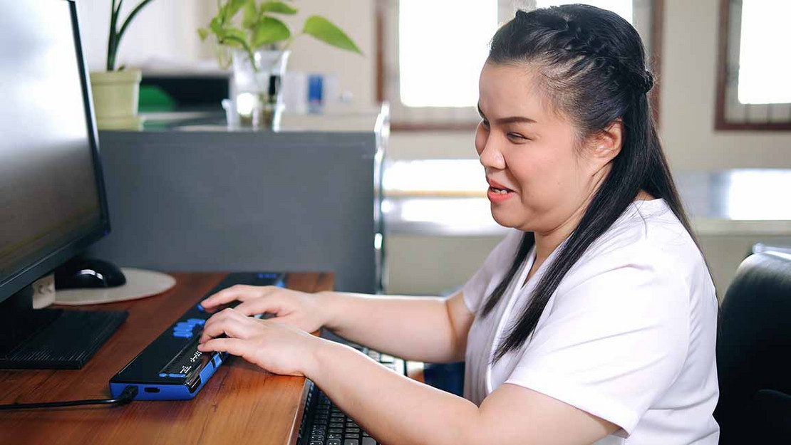 Blinde Frau arbeitet an einem Computer
