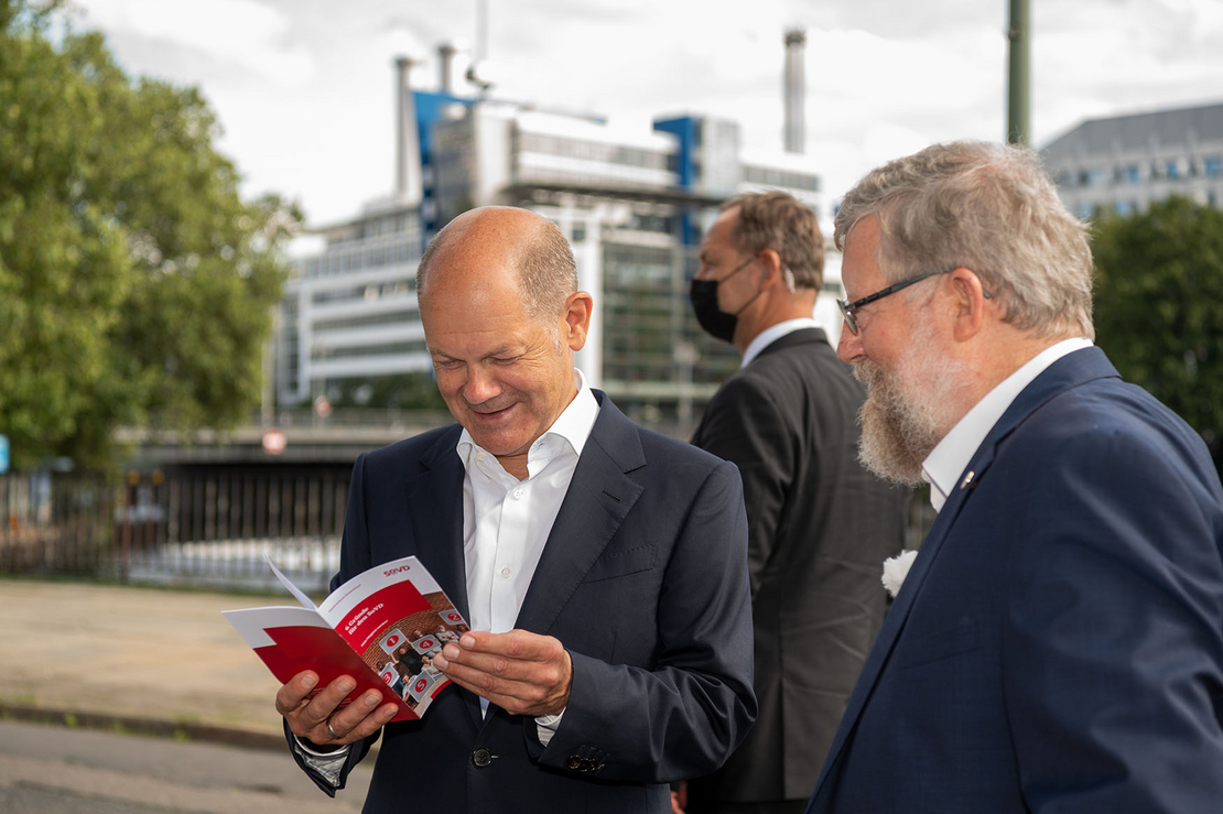 Kanzlerkandidat Olaf Scholz schaut sich mit Adolf Bauer eine SoVD-Broschüre an.