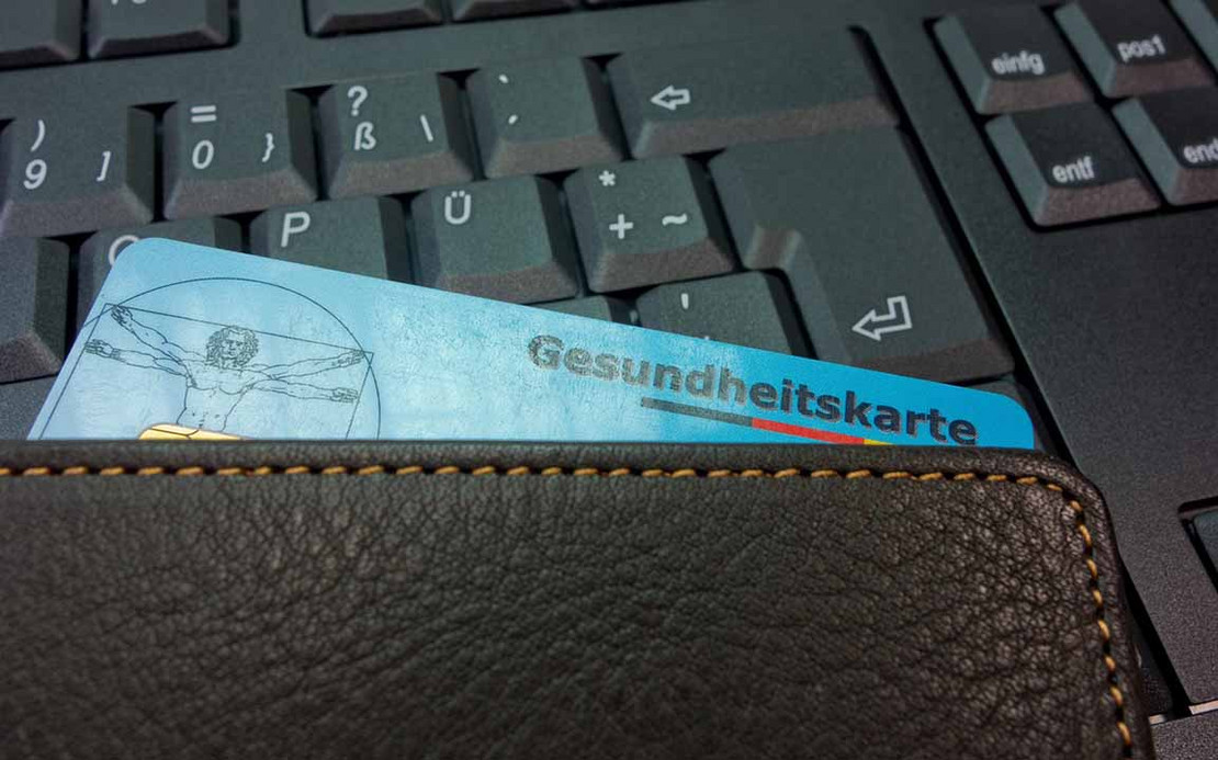 Eine Versichertenkarte liegt auf Tastatur eines Computers.
