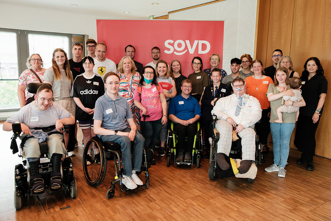 Gruppenbild: Jungen Menschen vor einer roten Leinwand mit SoVD-Logo. 