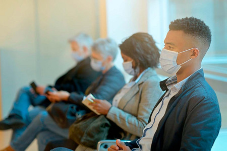 Mehrere Menschen mit Maske sitzen im Wartezimmer. 
