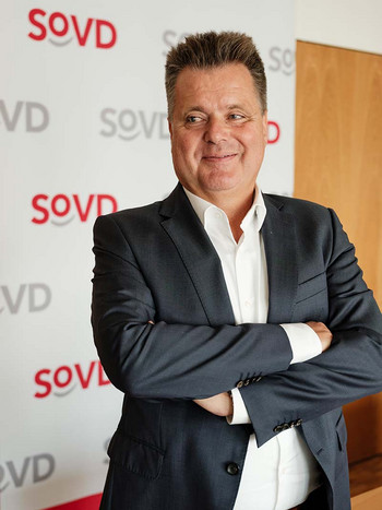 Jürgen Dusel vor einem Aussteller mit SoVD-Logos. 