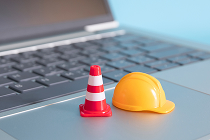 Eine Absperrung und ein Helm liegen auf einer Computertastatur.